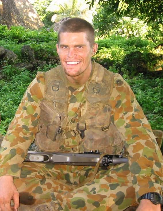 A portrait of a man smiling while wearing army uniform.