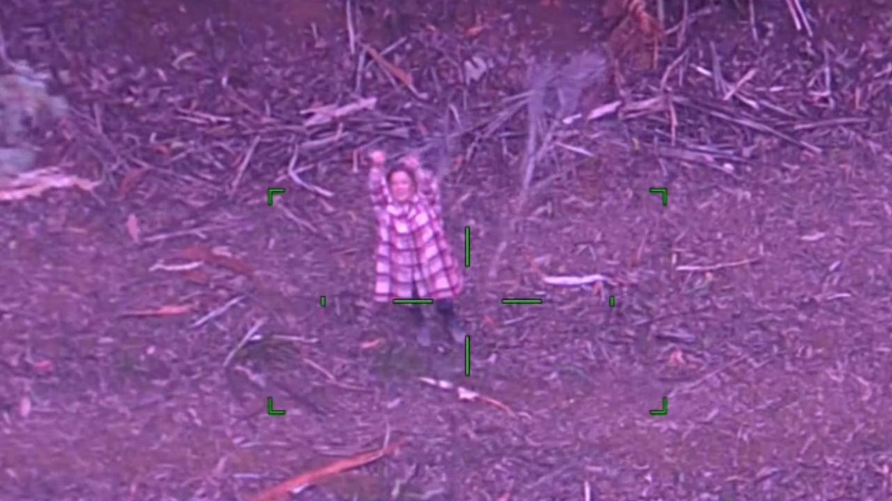 A photo from a helicopter of a woman down below with her arms outstretched.