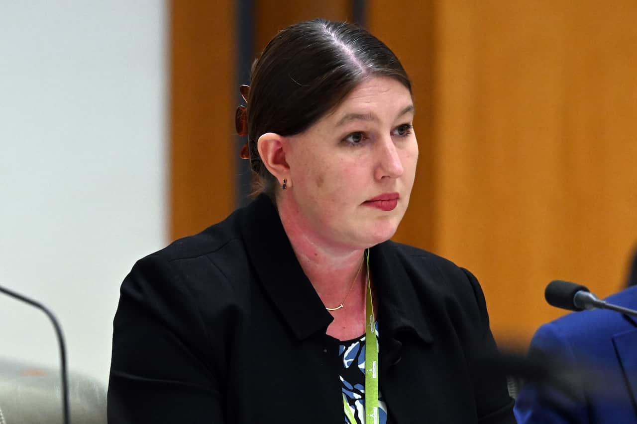 A woman in a black jacket sitting behind a microphone 