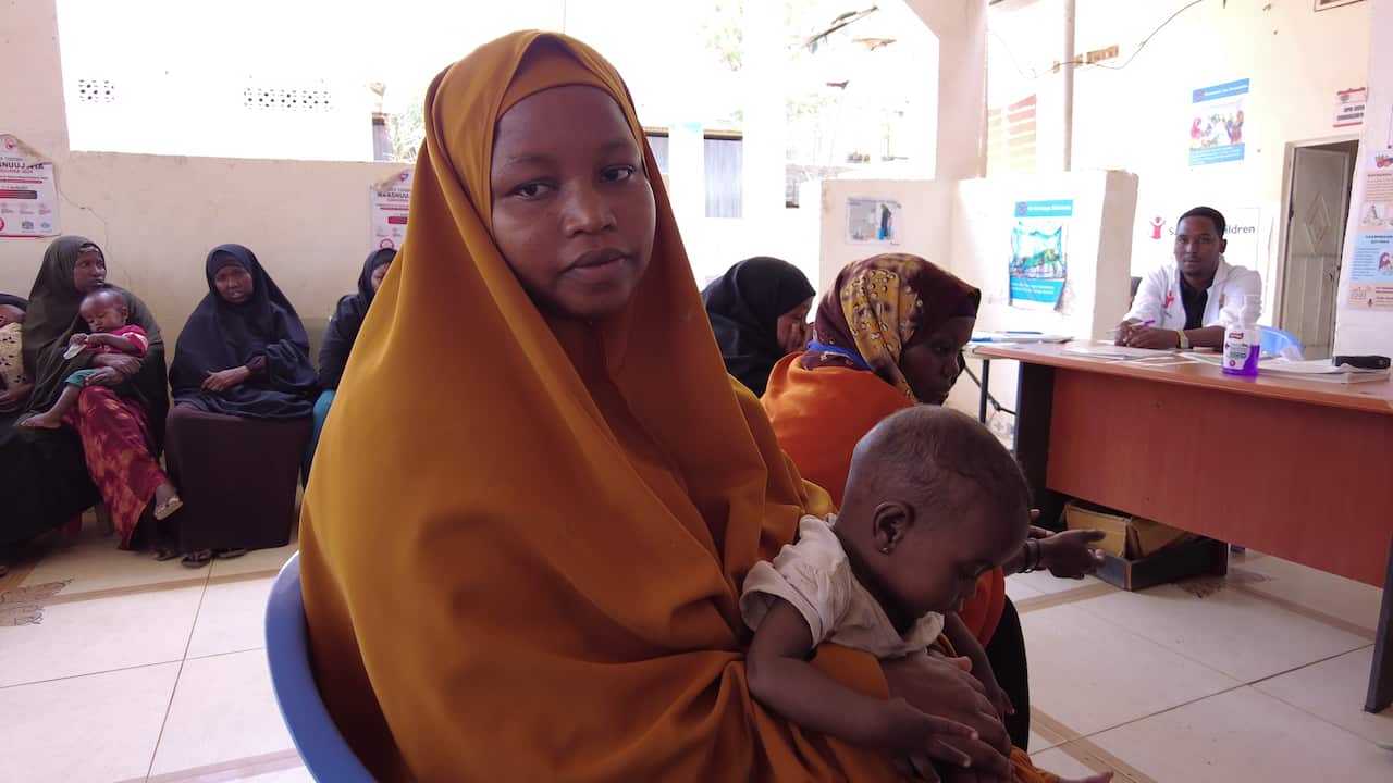 A woman holding her child while seated inside a clinic.