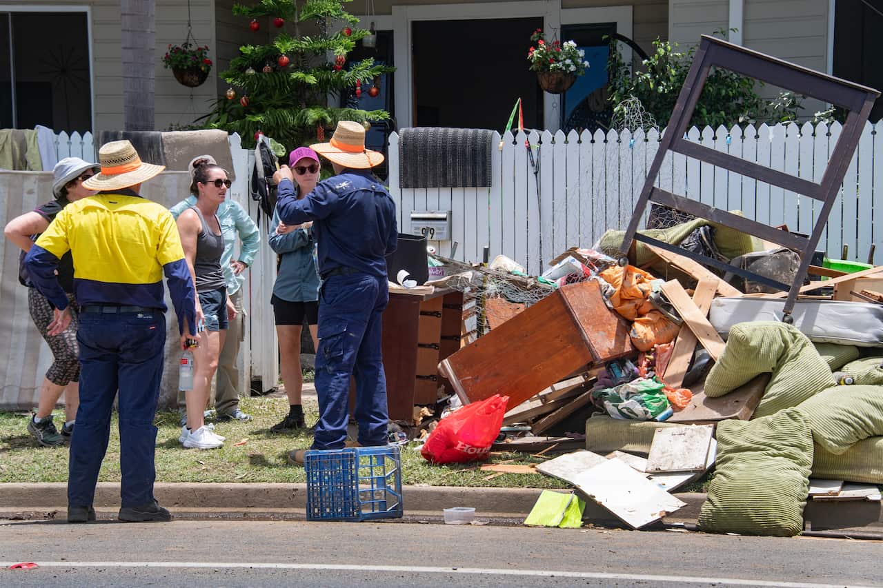 Volunteers arrive to help clean up a flooded house at Machans Beach in Cairns