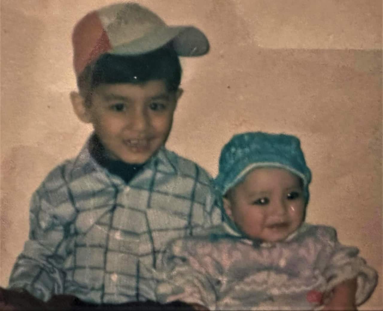 Kumail Jaffry (left) as a boy wearing a cap with a younger sibling.