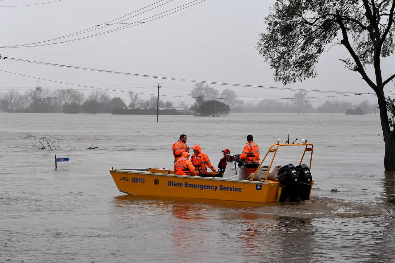 A NSW State Emergency Service (SES) crew is seen in a rescue boat as roads are submerged under floodwater