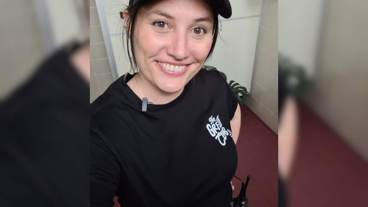 A smiling woman in a black t-shirt and black cap