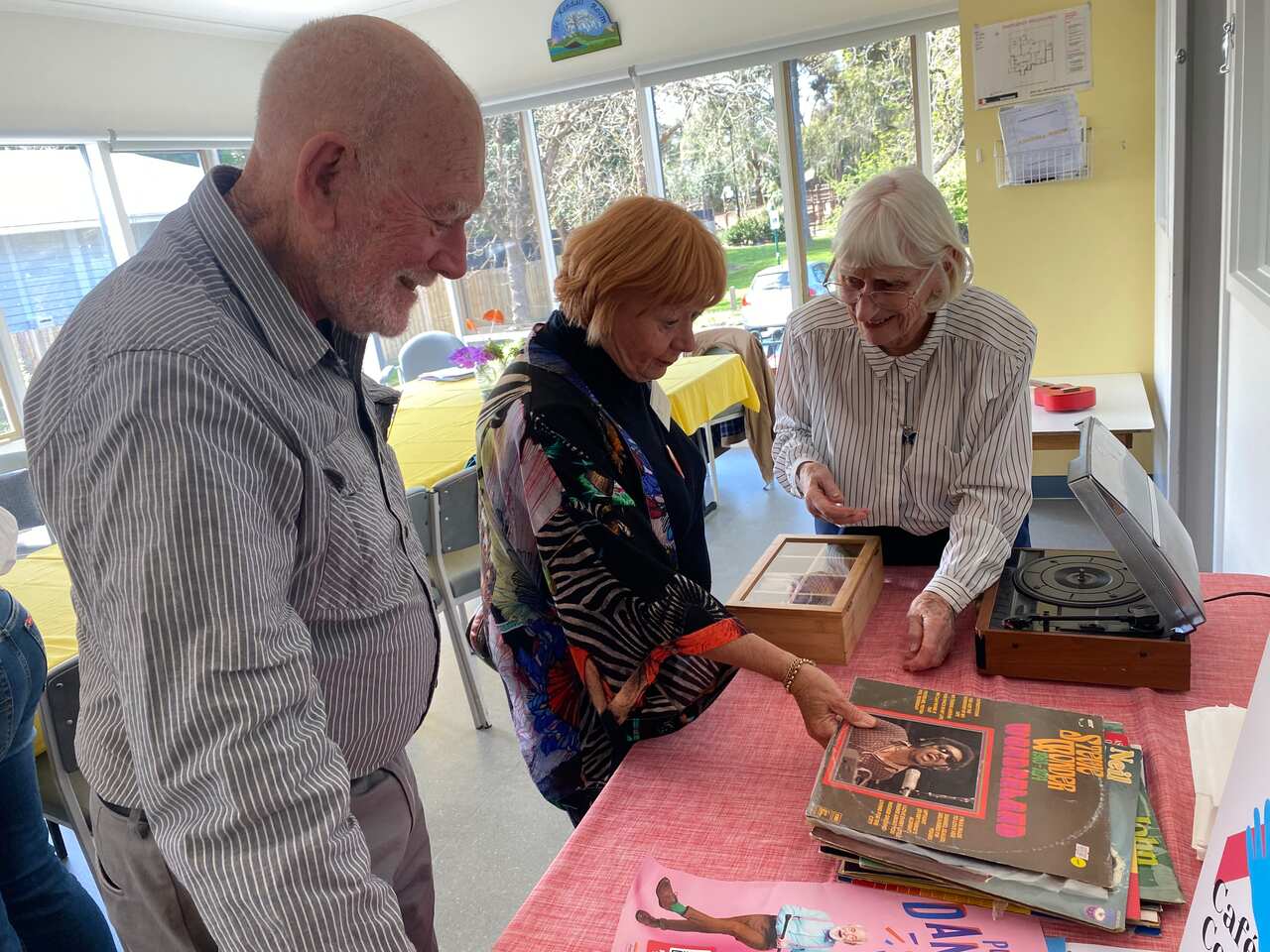 Three people looking at albums on a table.