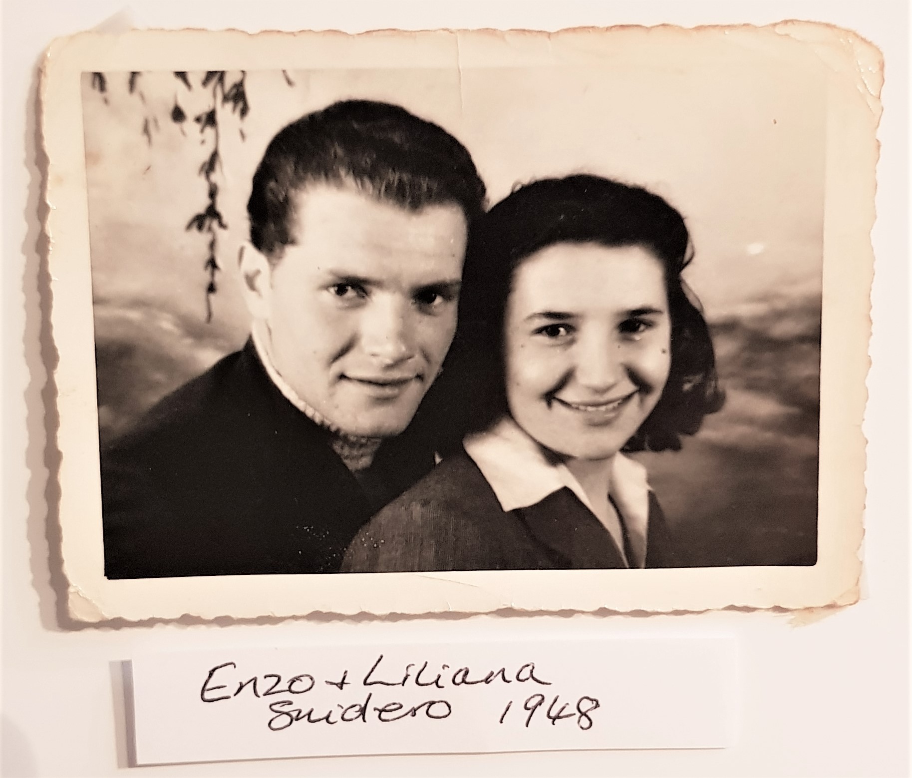 A vintage, black-and-white photograph shows a man and woman together.  The words "Enzo and Luciana Suicero" are written underneath.