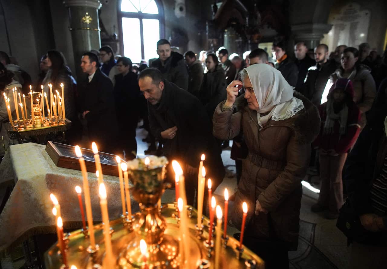 People are praying in the church with lit candles.
