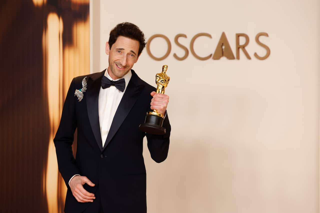A man holding an Oscars statuette