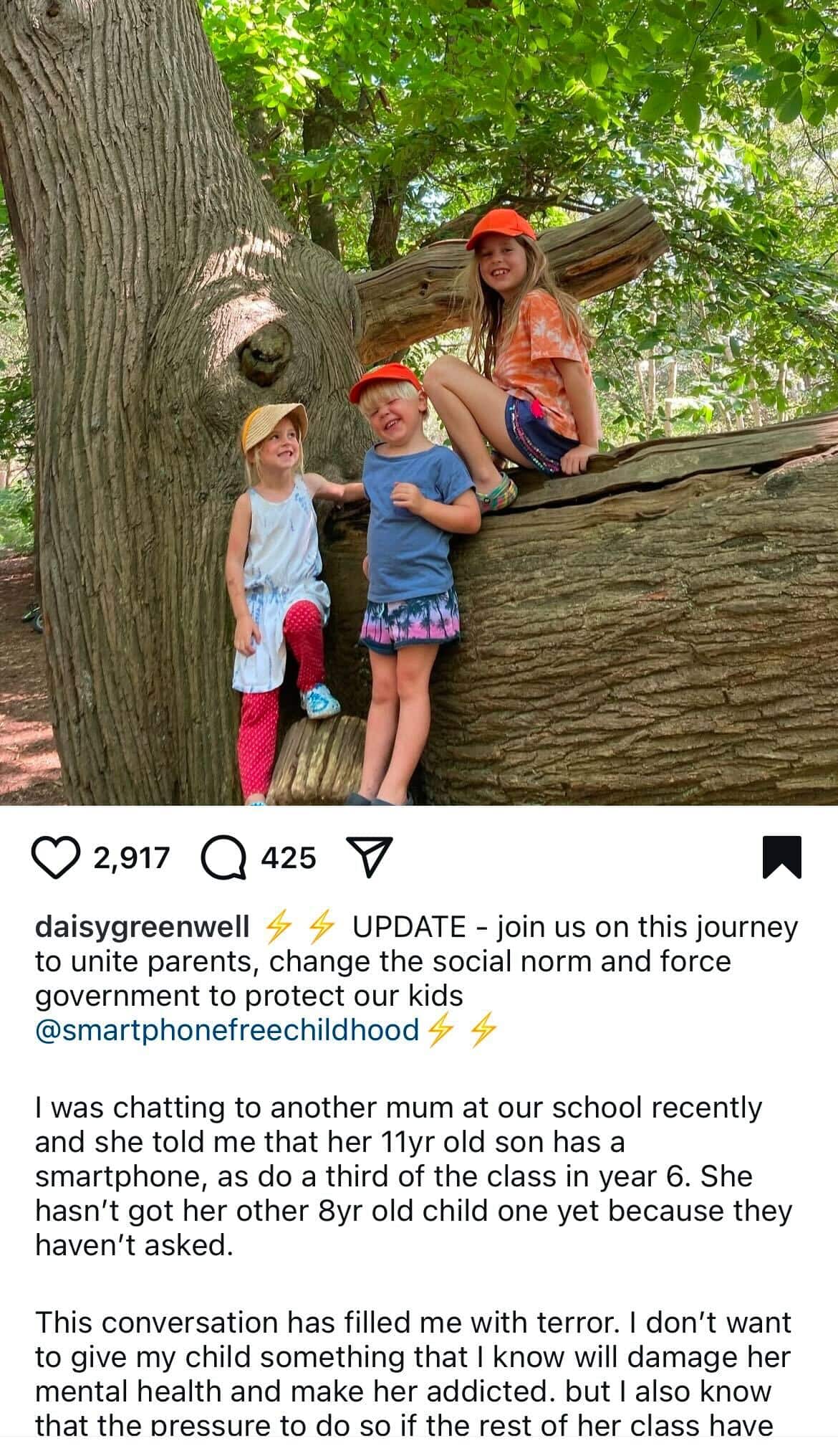 A screenshot of an Instagram post showing a photo of three young children standing next to a tree log and the text underneath it 