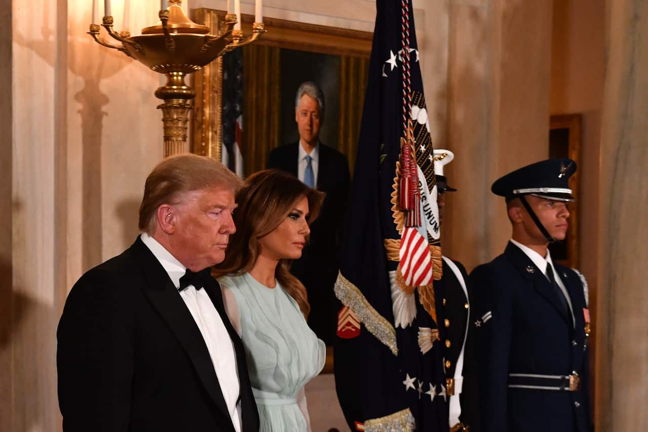 Man and woman stand in front of portrait.