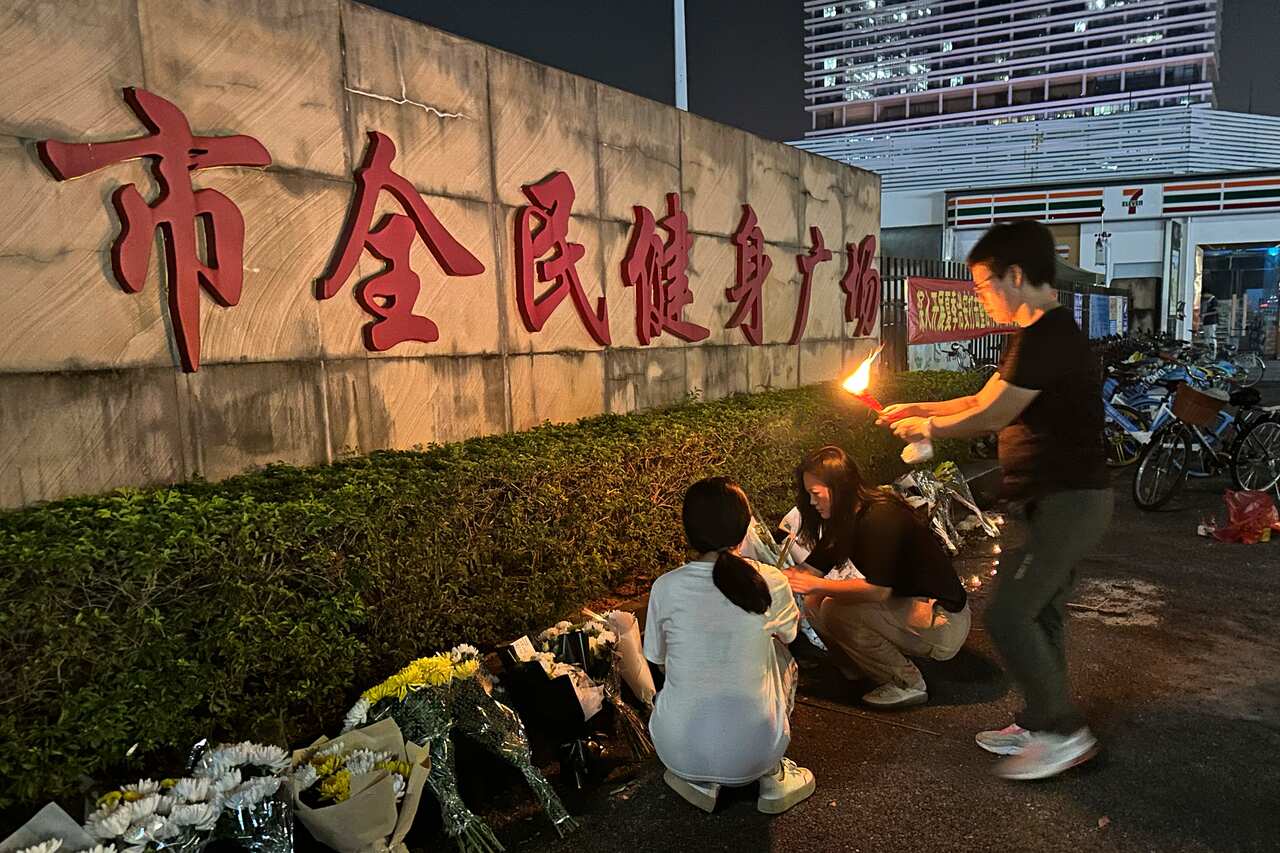 A woman lights a candle as offering near flowers
