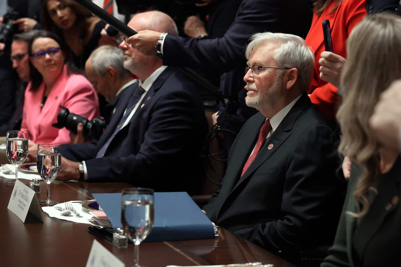 Kevin Rudd wearing a suit and tie and sitting at a desk in a room