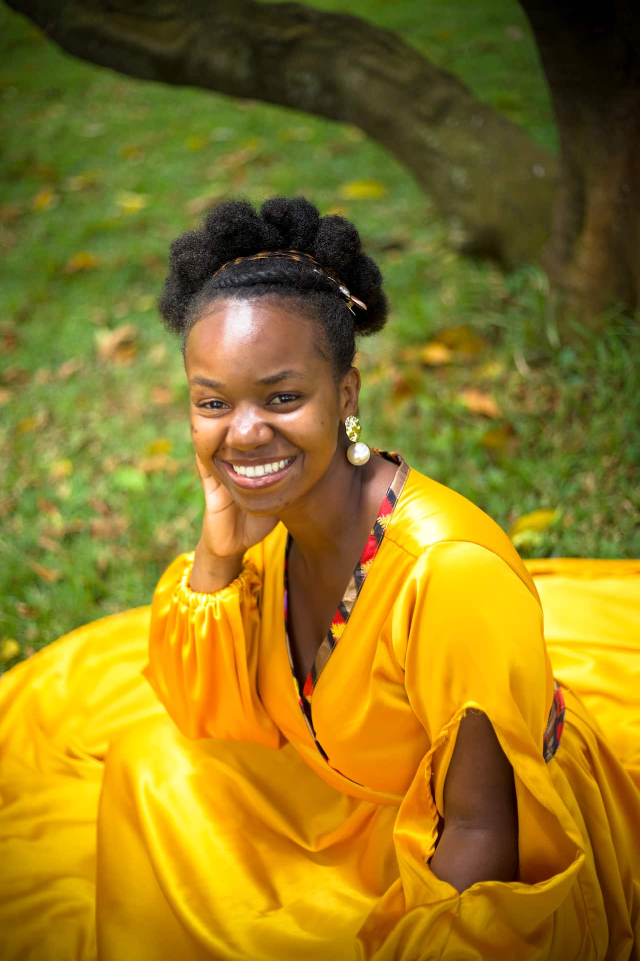 a woman in a yellow dress sitting on grass outside