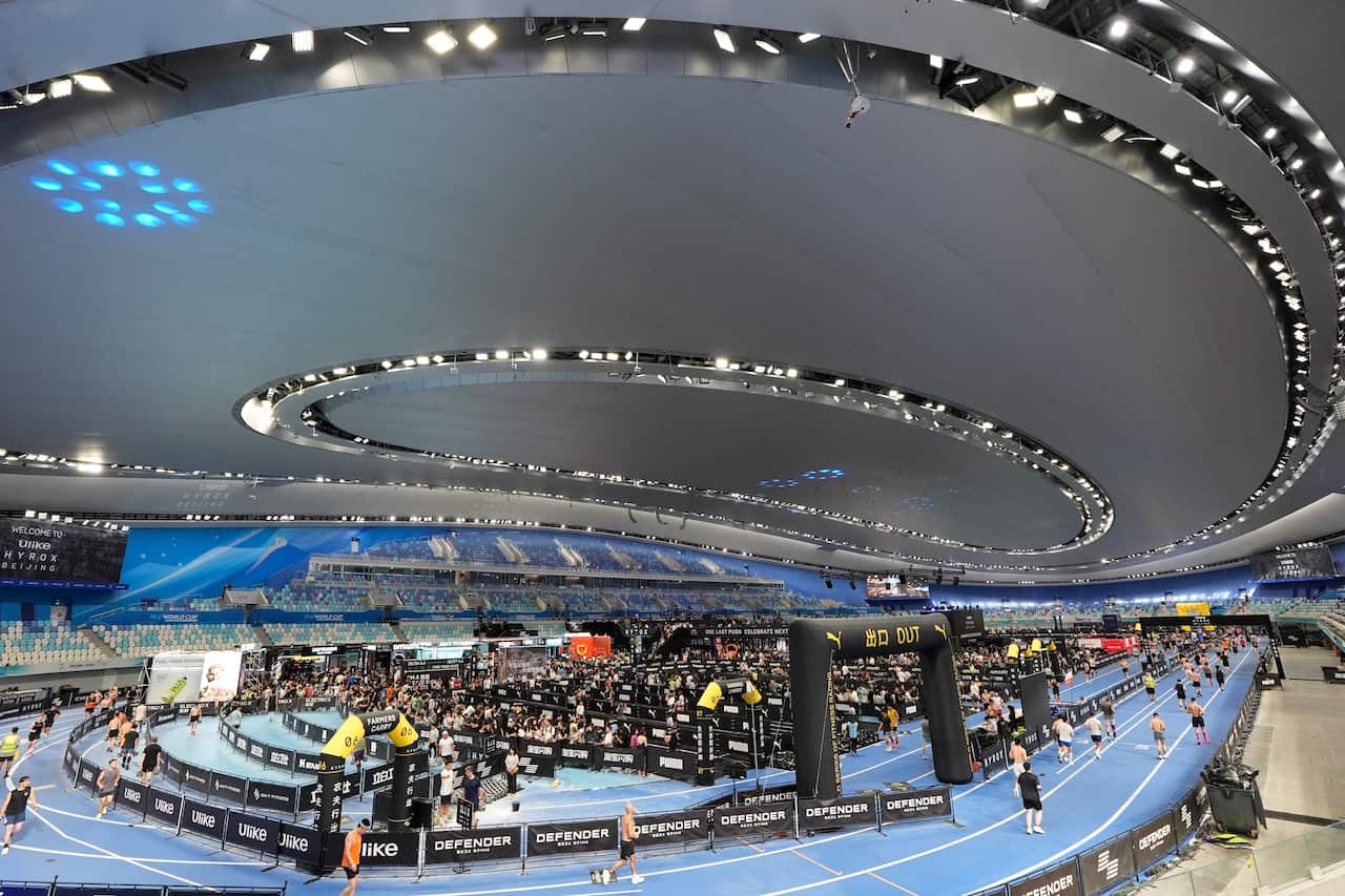 An indoor sporting arena with a blue track and black equipment.