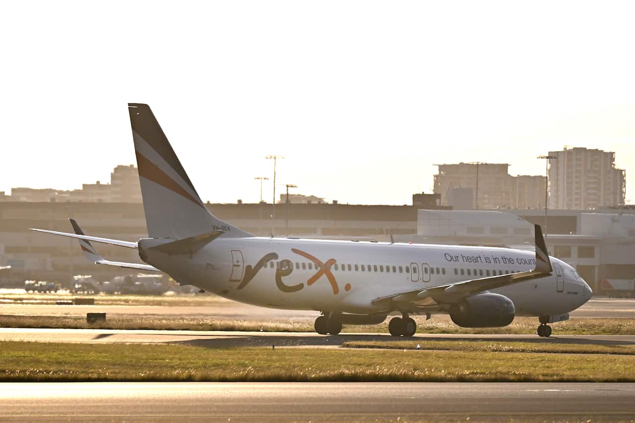 A Rex Airlines plane taxis along the runway of an airport. 