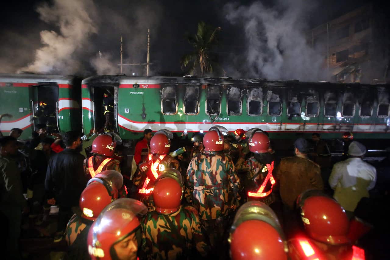 Rescue personnel search through a burnt out carriage