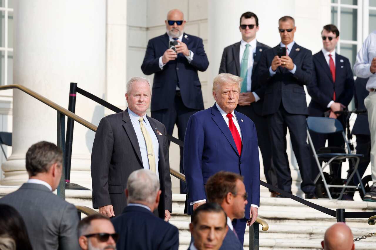 Donald Trump walking down a flight of stairs, surrounded by men in suits.