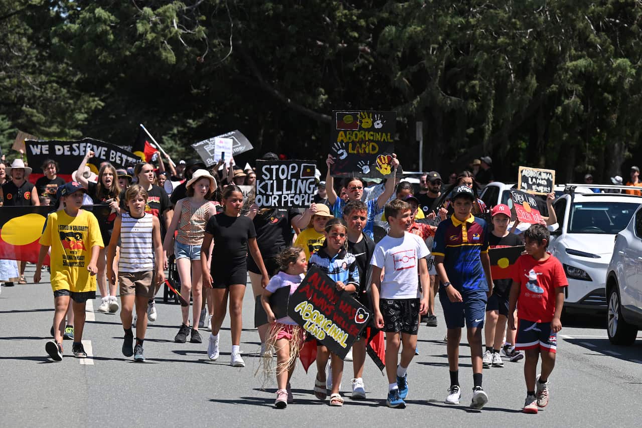 People walking along a street holding signs.
