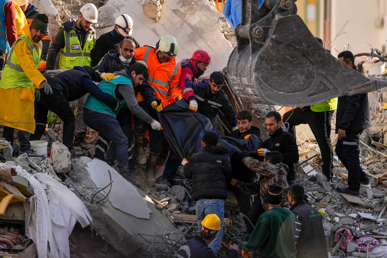 Rescue workers carry a body bag over rubble