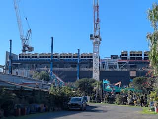 A large building under construction in a suburban street.