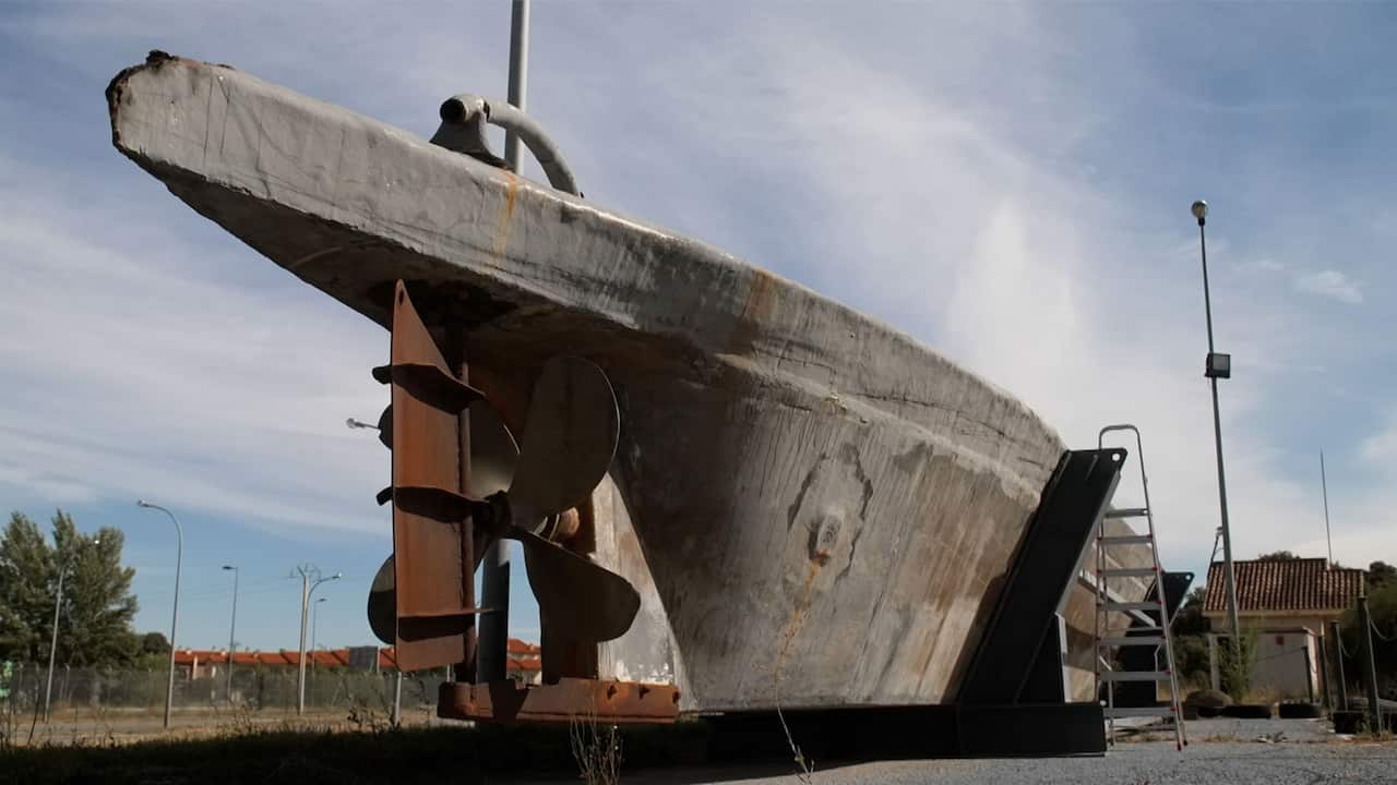 A large semi-submersible vessel hauled ashore for public viewing, with a ladder next to it 
