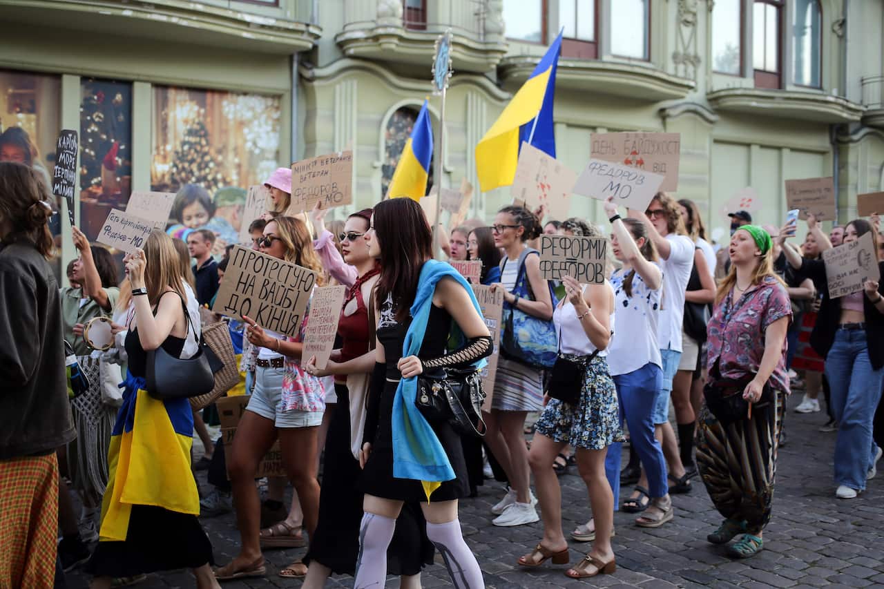 Activists carrying placards and holding Ukrainian flags while marching down a street