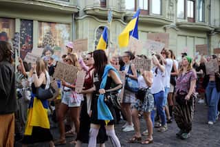Activists carrying placards and holding Ukrainian flags while marching down a street