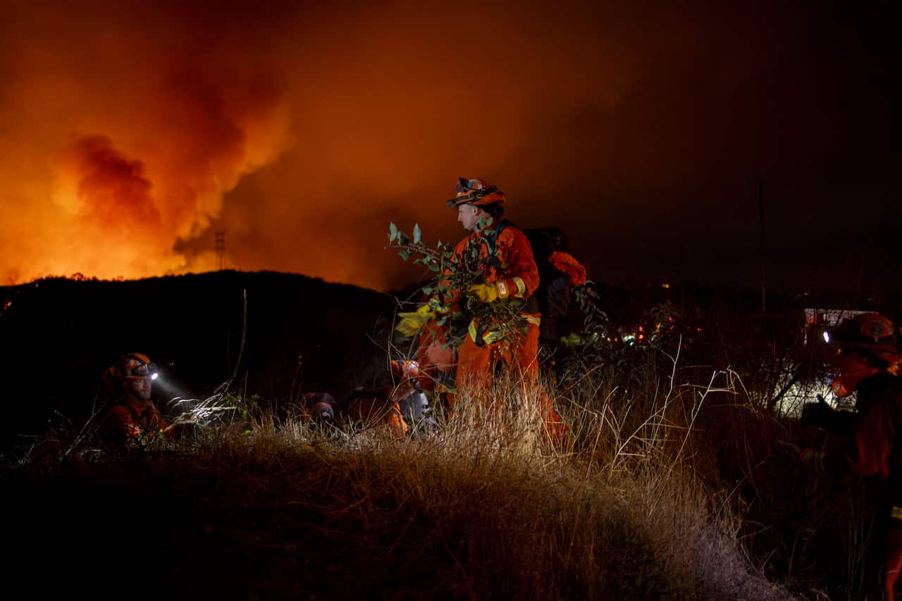 Firefighters clear branches ahead of fire