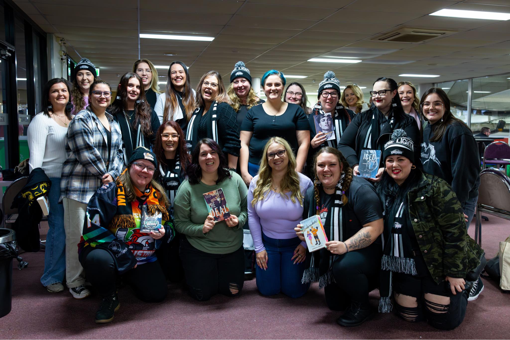 A group of people, some holding books and others wearing beanies and scarves
