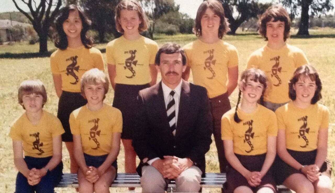 Eight students and a teacher in a class photo taken outside