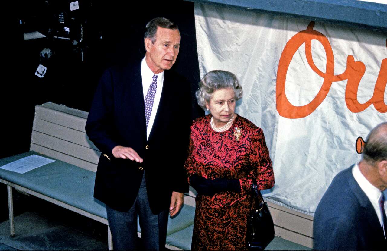 Then US President George HW Bush stands next to Queen Elizabeth II. 