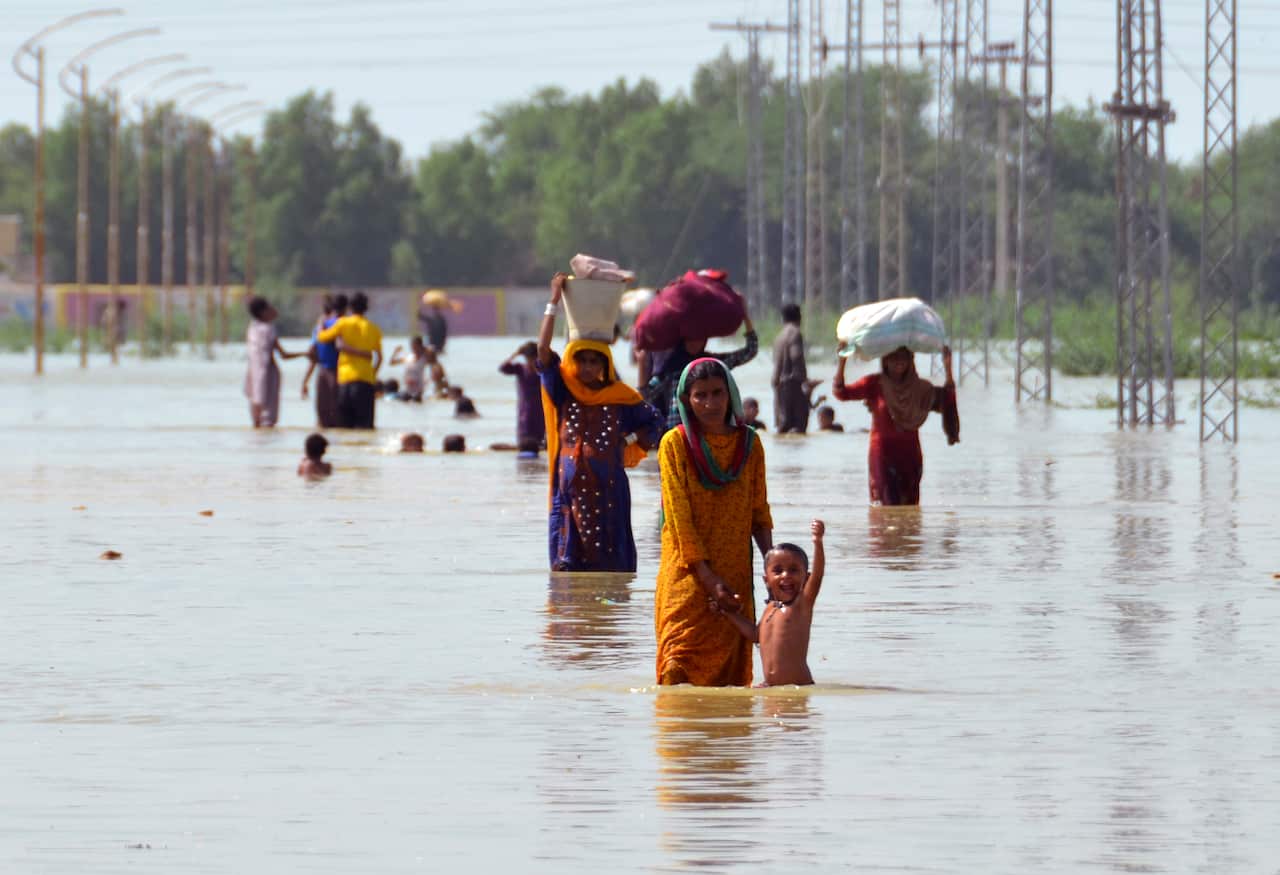 Displaced people carry belongings after they salvaged usable items from their flood-hit home 