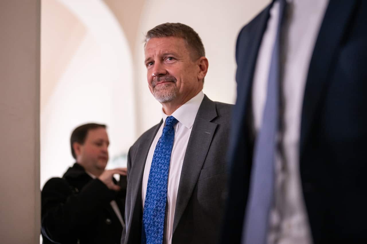 A man wearing a suit and tie standing indoors.