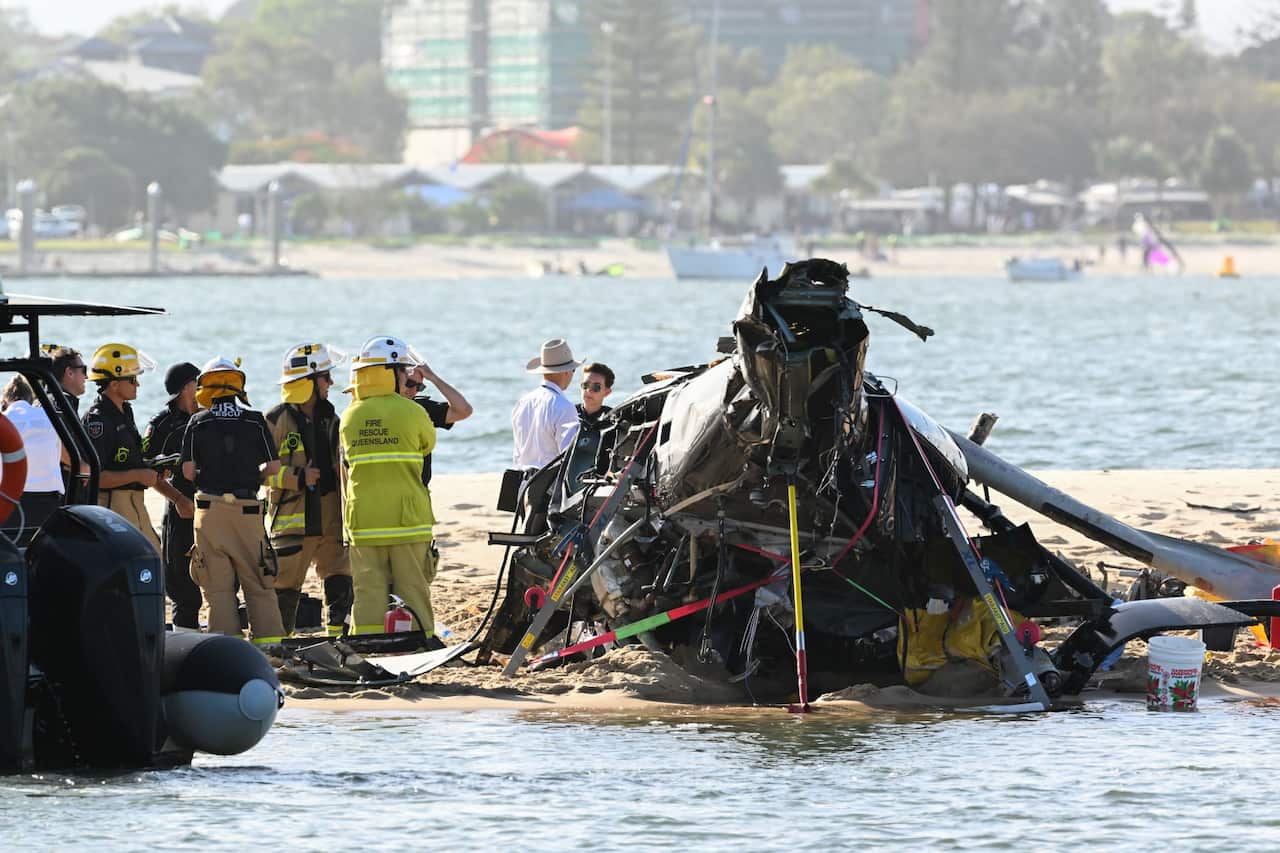 Police and Fire and Rescue personnel inspect a helicopter at the scene of a helicopter collision near Seaworld, on the Gold Coast, Monday, January 2, 2023. 