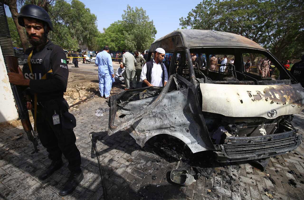 People inspect a destroyed car.