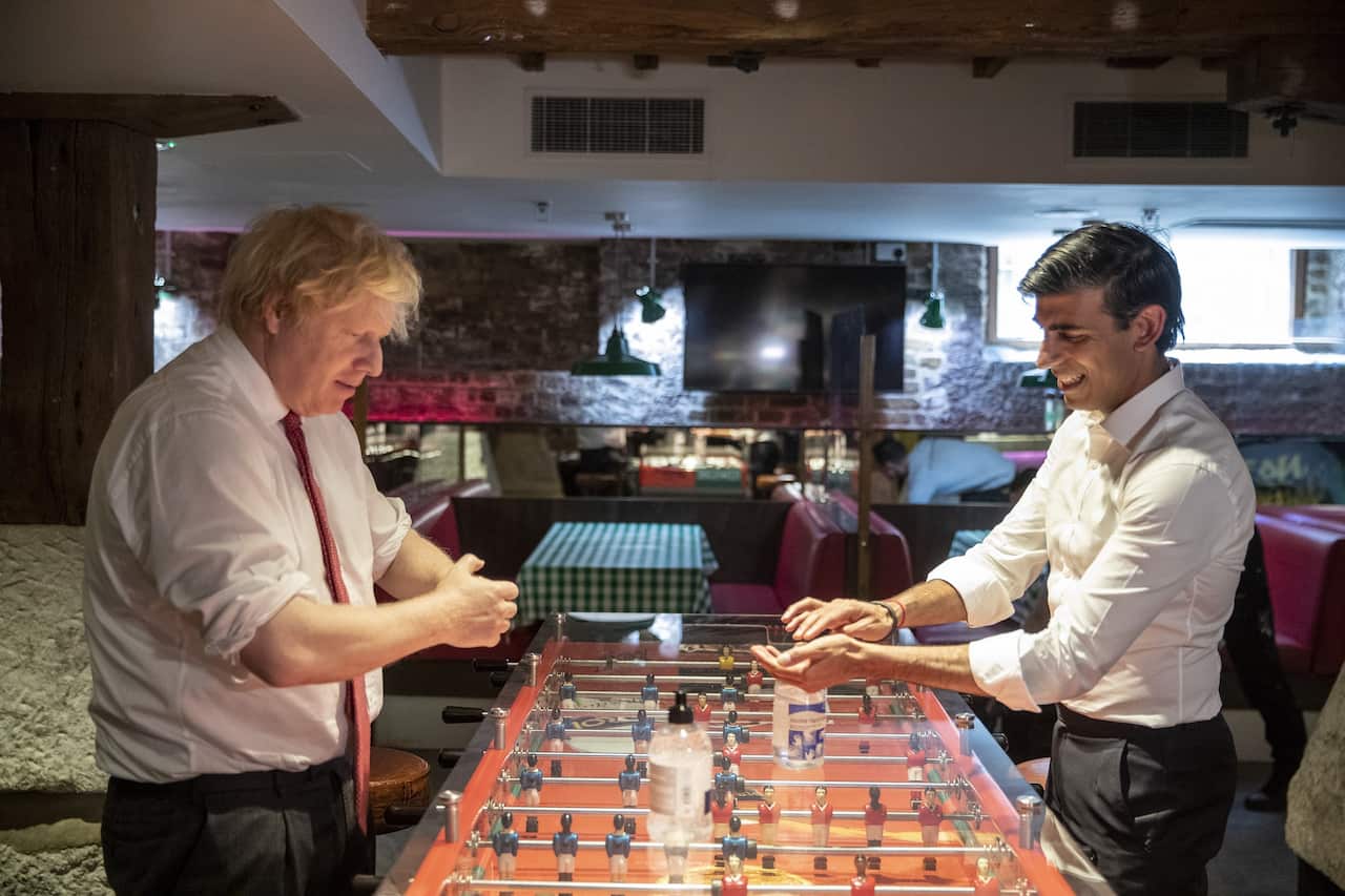 Caretaker Prime Minister Boris Johnson (left) and the Chancellor of the Exchequer Rishi Sunak (right) use hand sanitiser during a visit to the Pizza Pilgrims restaurant in east London on 26 June 2020. 