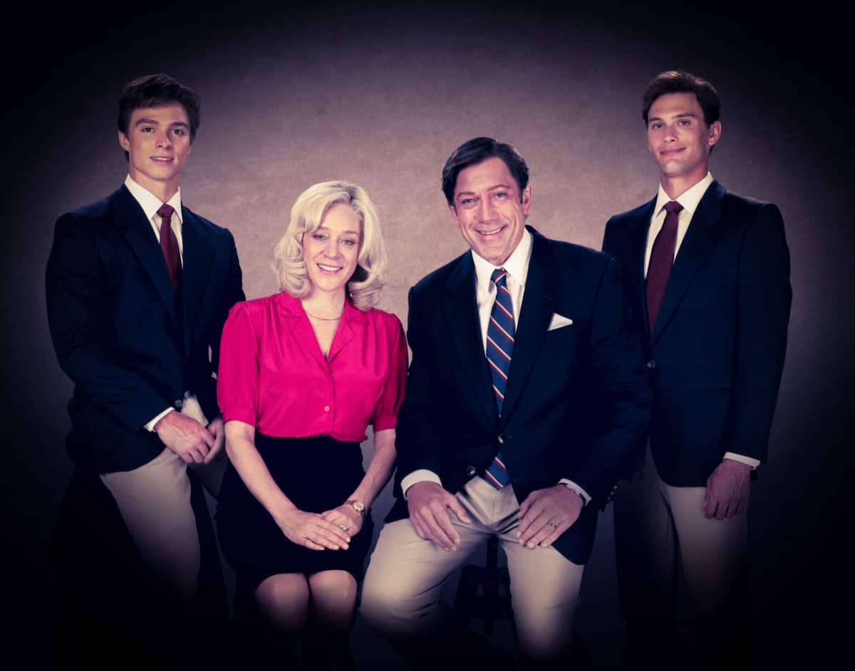 Four actors posing for a promotional photo. Three men in dark blazers and ties and light-coloured pants and ties are with a woman wearing a red top and black skirt.