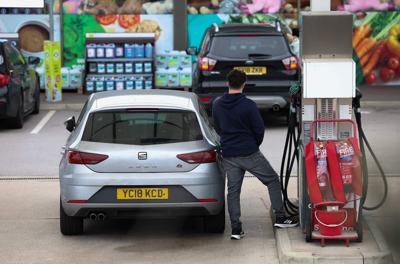A man filling up his car with petrol at a service station.