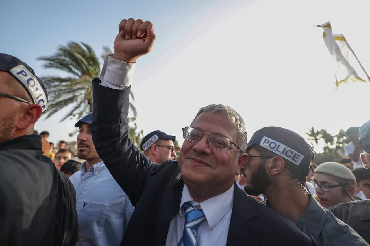 A man in a tight crowd waves an arm in the air surrounded by police