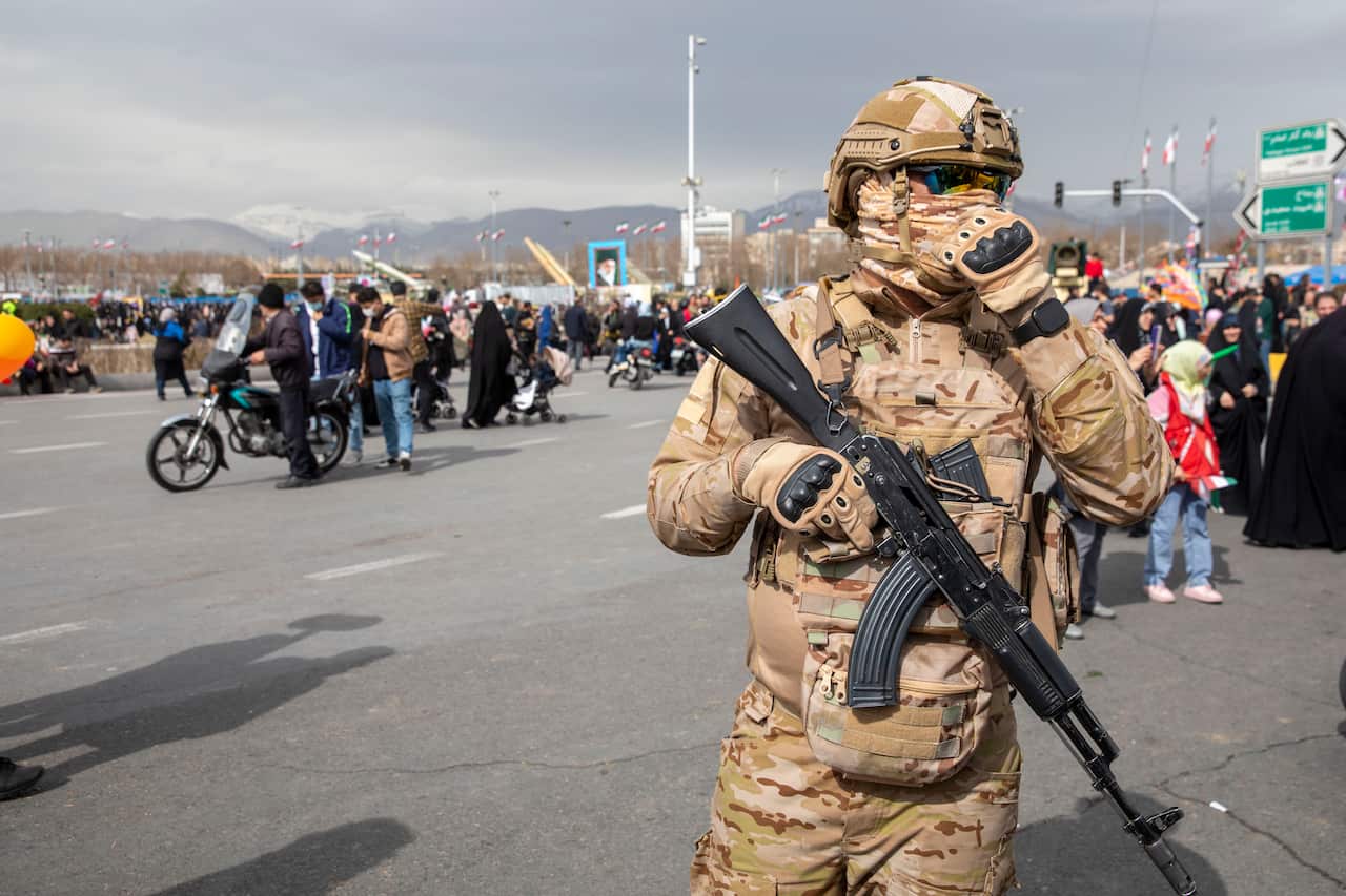 A man wearing camouflage gear and holding a large gun