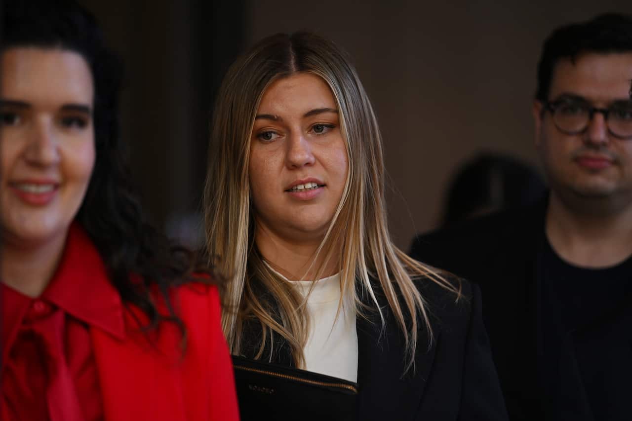 A woman in a witness stand in between two other people