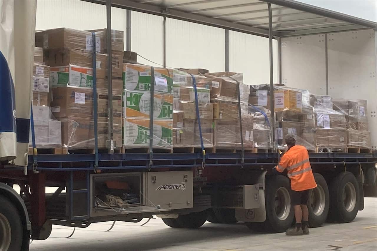 A man standing next to a truck loaded with boxes