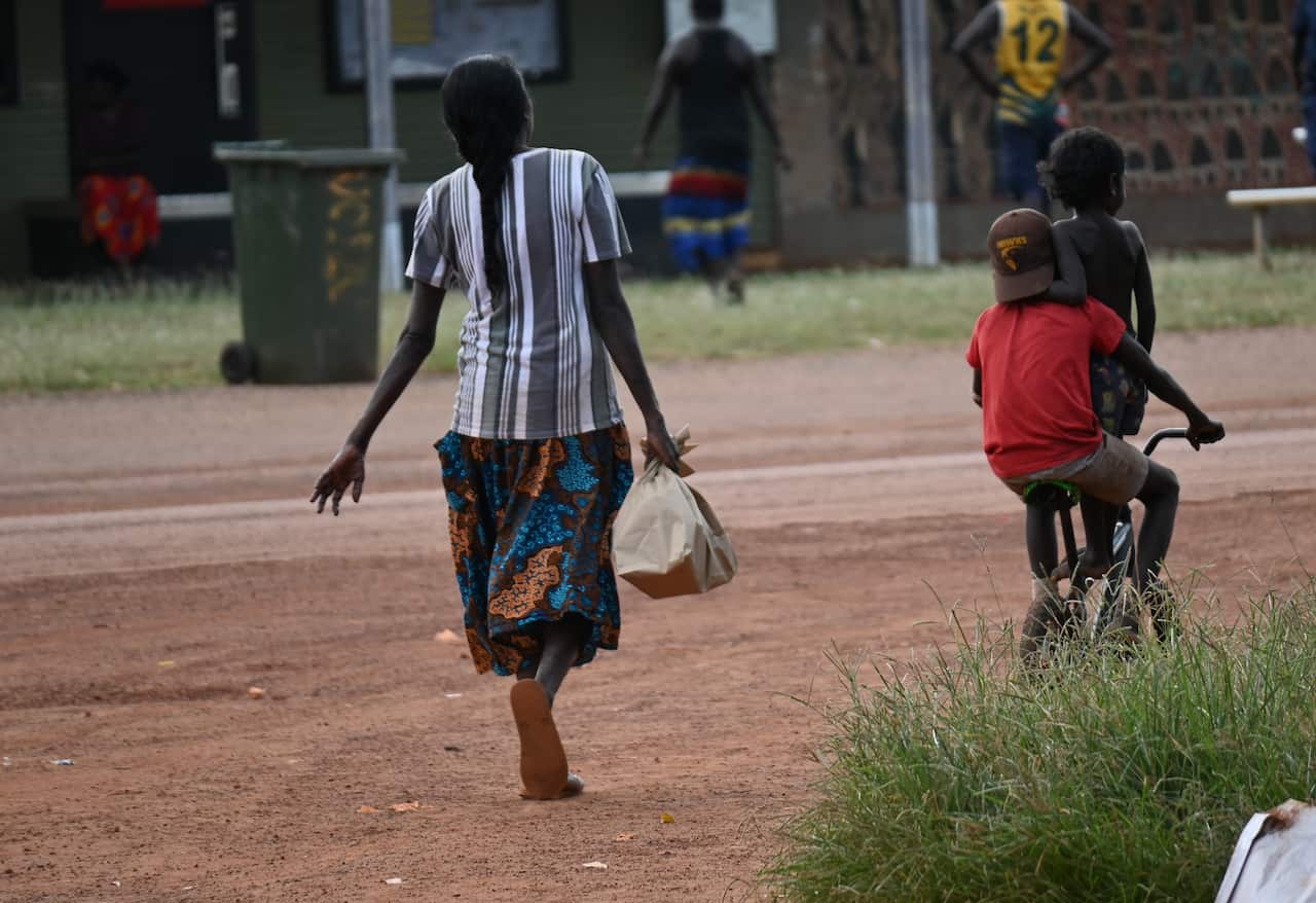 A woman leaves the only supermarket in Ramingining holding a bag of shopping.