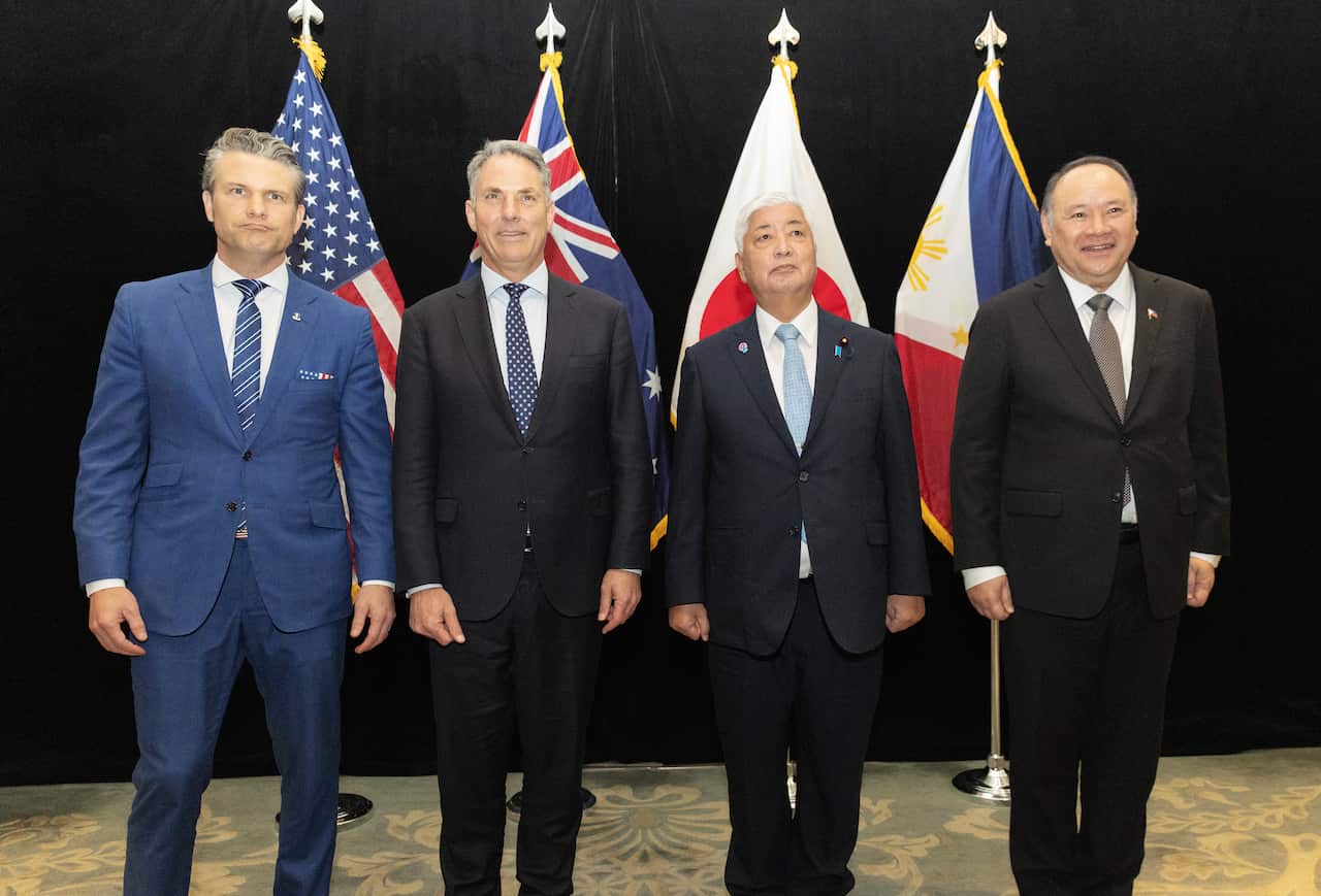 Four men in suits pose for a picture standing in a row
