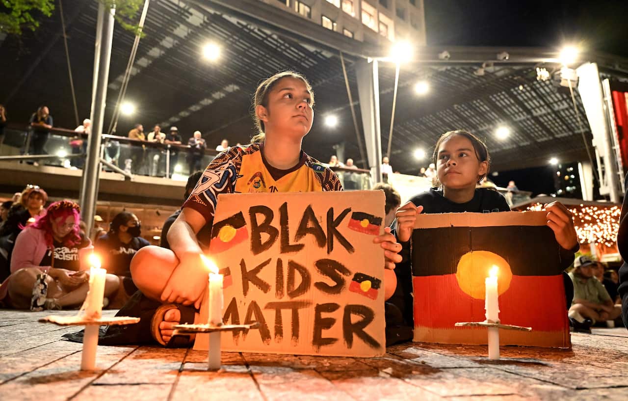 Aboriginal youths in Brisbane hold a sign reading 'Blak kids matter'. 