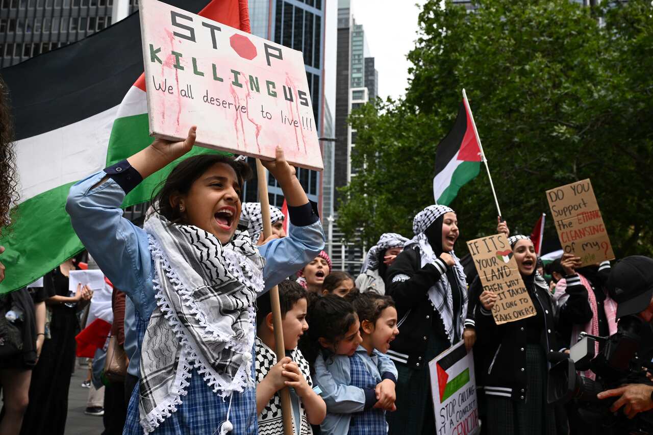 Students, some of primary school age, hold up signs protesting the killing of children in Gaza.
