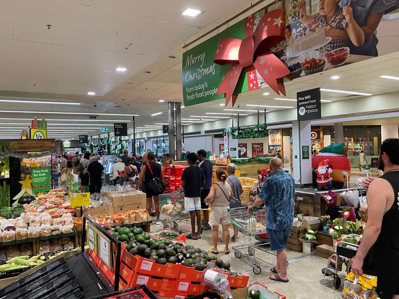 People walk through the fruit and vegetable section of a supermarket.