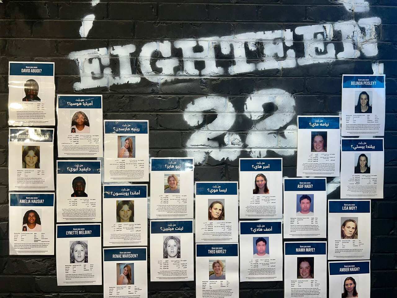Posters in Arabic are stuck on a cafe wall with the name EIGHTEEN22 on it. 