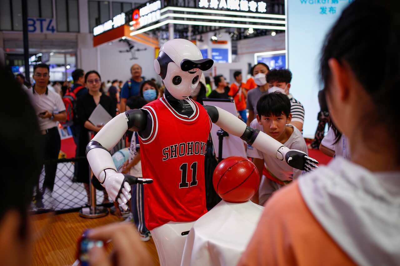 A robot wearing a basketball jersey walks as people look on. 