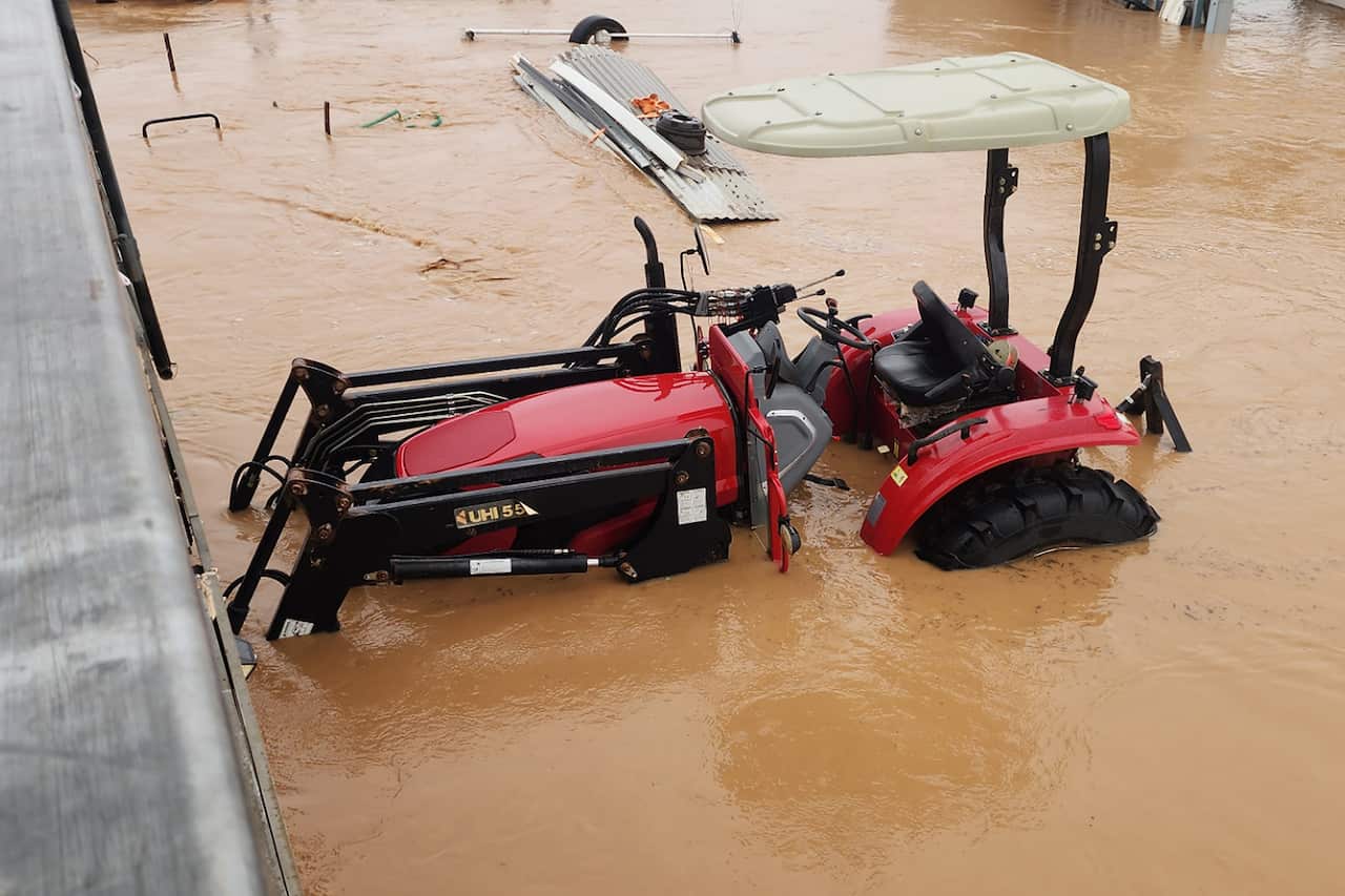 A tractor sits in a flooded yard.